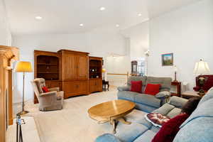 Spacious living area featuring vaulted ceilings, recessed lighting, and soft carpet flooring