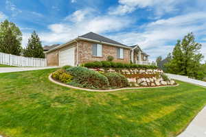 Brick exterior residence with a sloped front lawn and a terraced rock garden