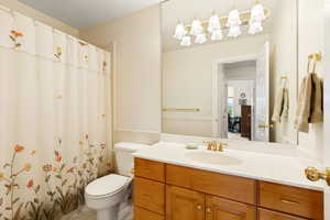 Bathroom featuring a wood-finish vanity with a built-in sink, a large wall-mounted mirror, and a multi-bulb light fixture