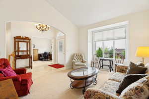 Living area featuring neutral carpeting, an arched doorway, and a large front window with a pleated shade