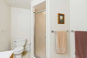 Bathroom featuring a white toilet, enclosed shower with frosted glass, and chrome towel bars