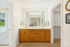 Double vanity with wood cabinetry, integrated sinks, white countertop, and gold-tone fixtures