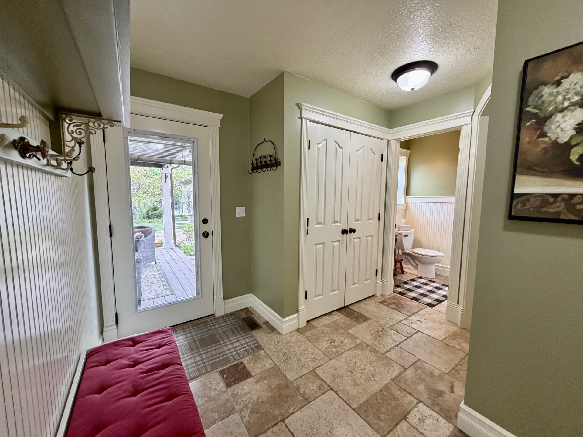 Entryway with natural stone-look tile flooring, white beadboard paneling, and a full-light exterior door