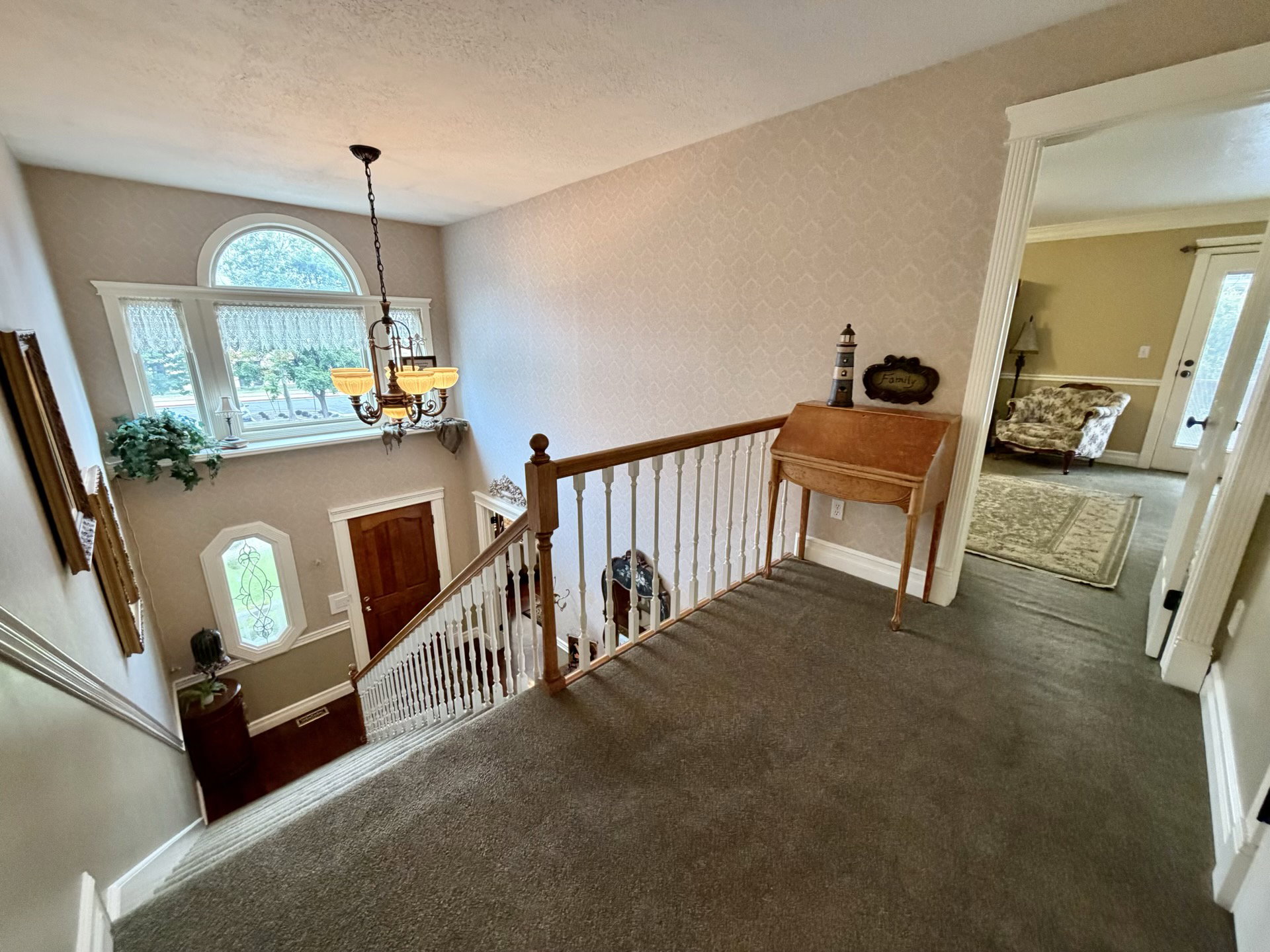Two-story foyer featuring a chandelier, arched window, and decorative sidelight