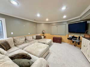 Recessed lighting illuminates this carpeted room featuring painted walls with wood paneling and crown molding