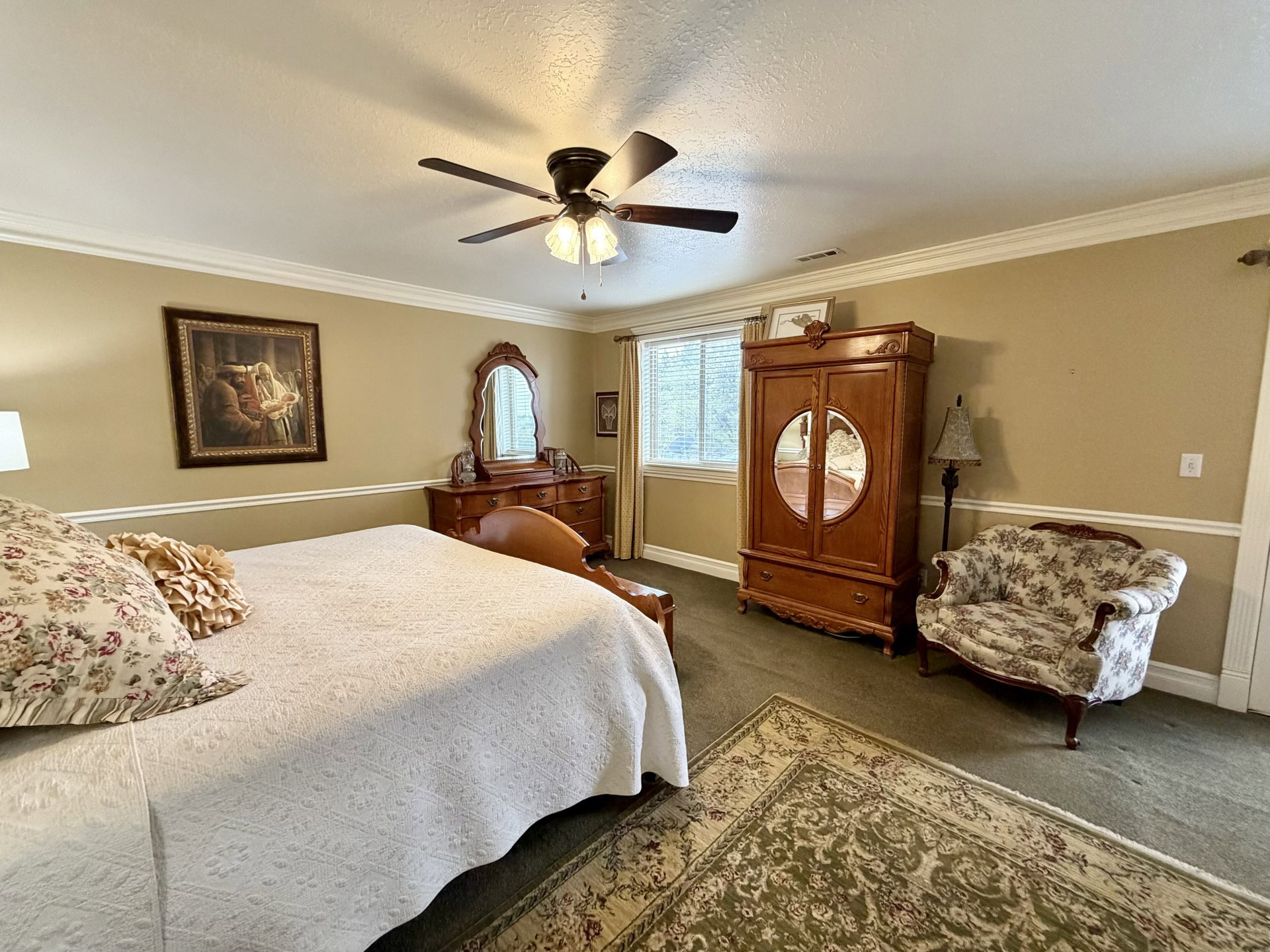 Carpeted room featuring a ceiling fan, crown molding, and chair rail detailing