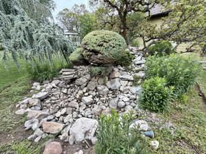 Garden landscaping featuring a dry creek bed, varied rock formations, and mature plantings