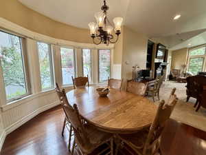 Dining area with a bay window, wood-finish flooring, and wainscoting