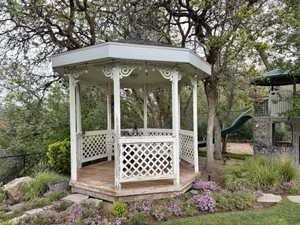 White octagonal gazebo with decorative lattice work, wood-finish flooring, and string lighting