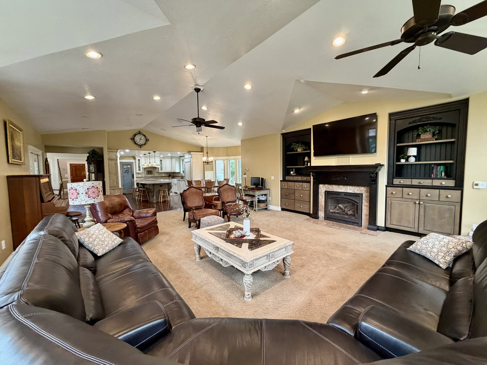 Spacious living area featuring vaulted ceilings, recessed lighting, and ceiling fans