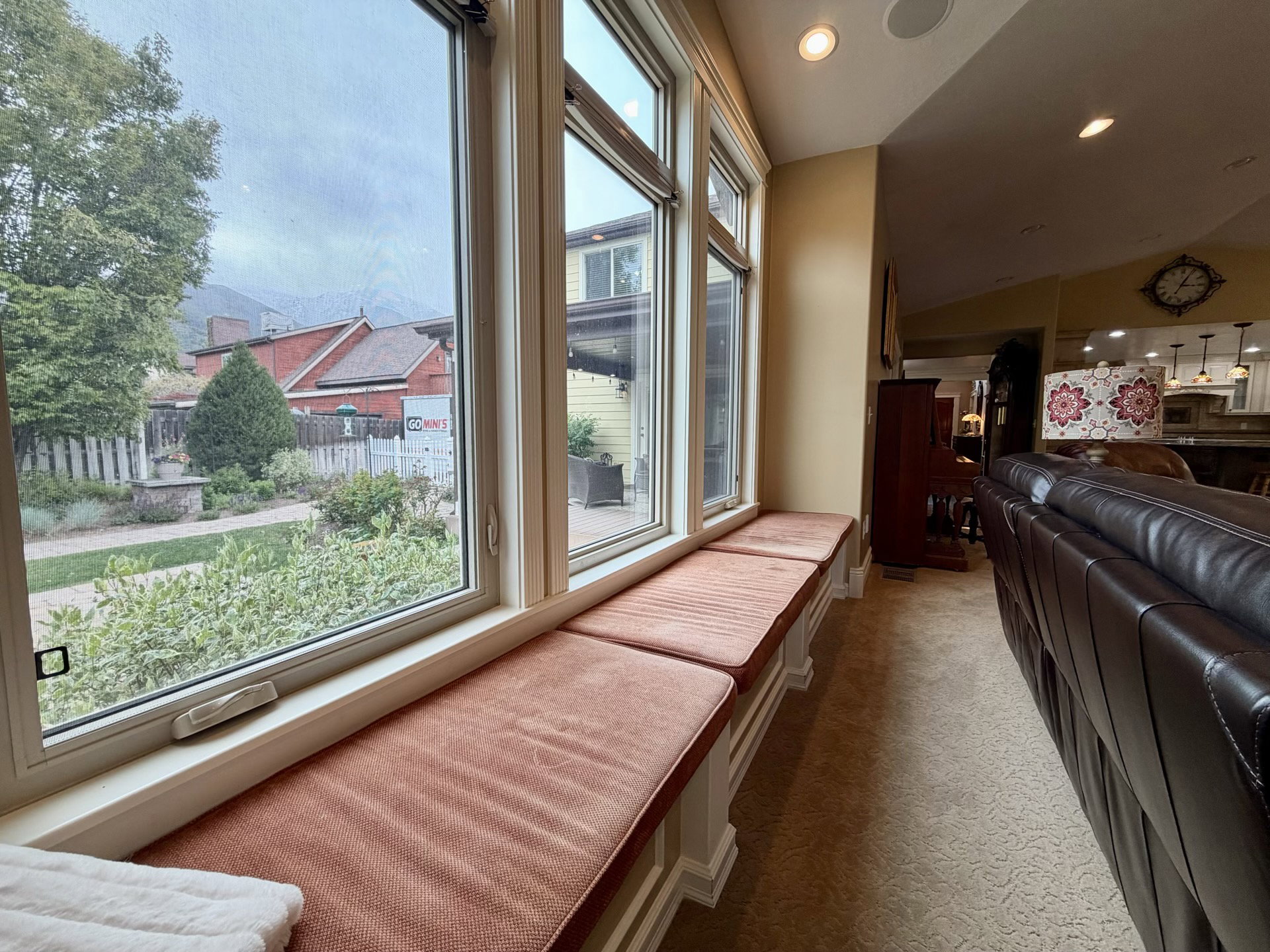 Expansive window seat with built-in storage, natural wood window trim, recessed ceiling lighting, and textured carpeting