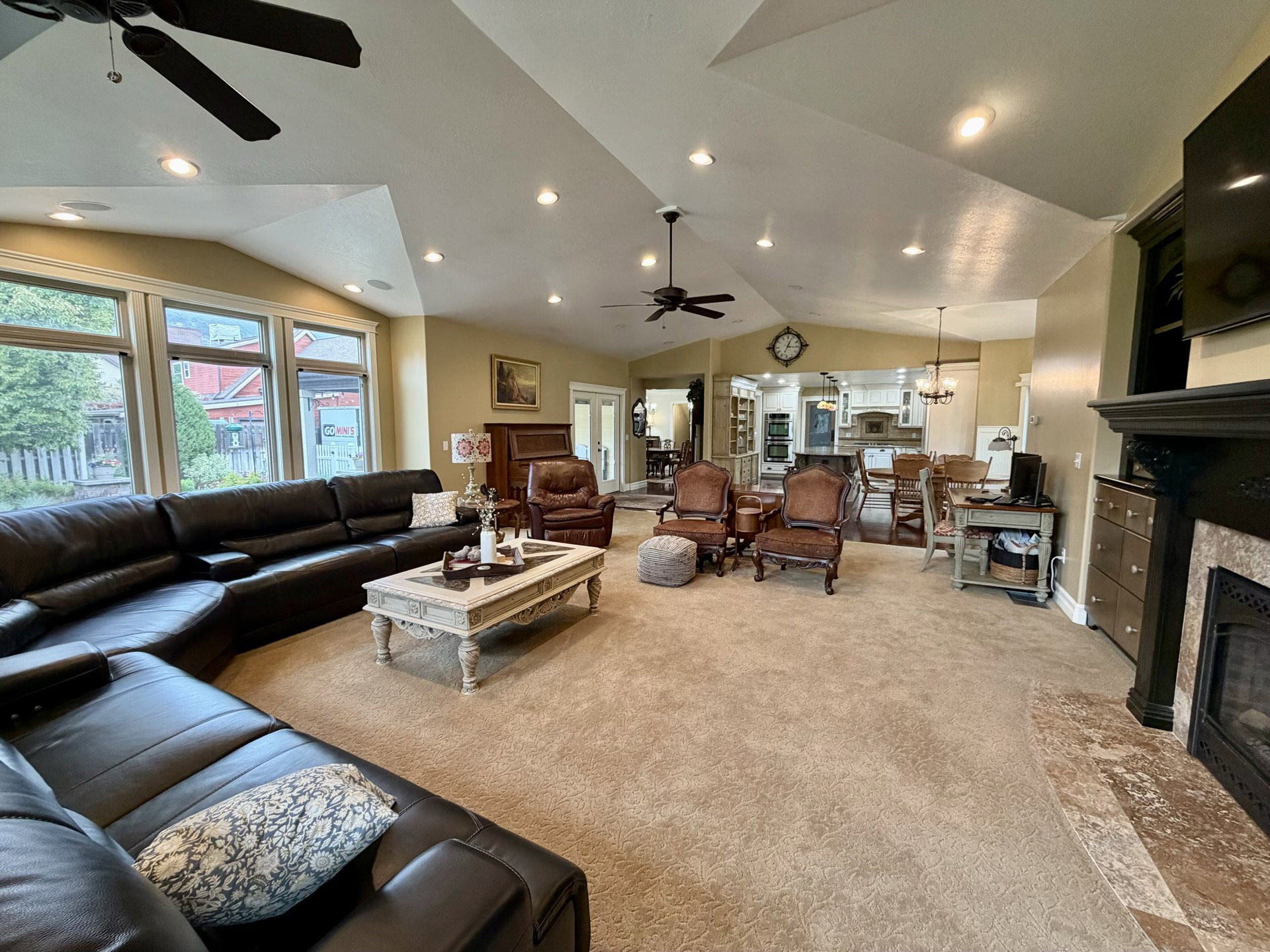 Expansive living area featuring vaulted ceilings, recessed lighting, and a prominent fireplace with a stone surround