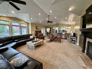 Expansive living area featuring vaulted ceilings, recessed lighting, and a prominent fireplace with a stone surround