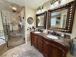 Dual vanity with ornate wood cabinetry and dark stone countertops