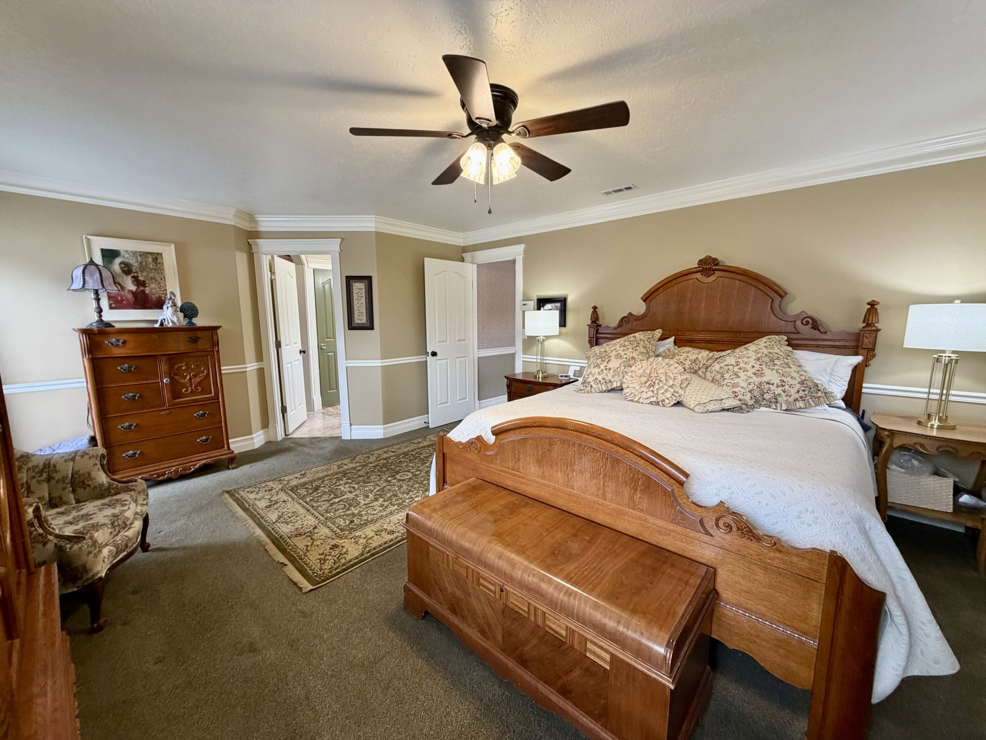 Spacious room featuring a ceiling fan with integrated lighting, crown molding, and chair rail detailing