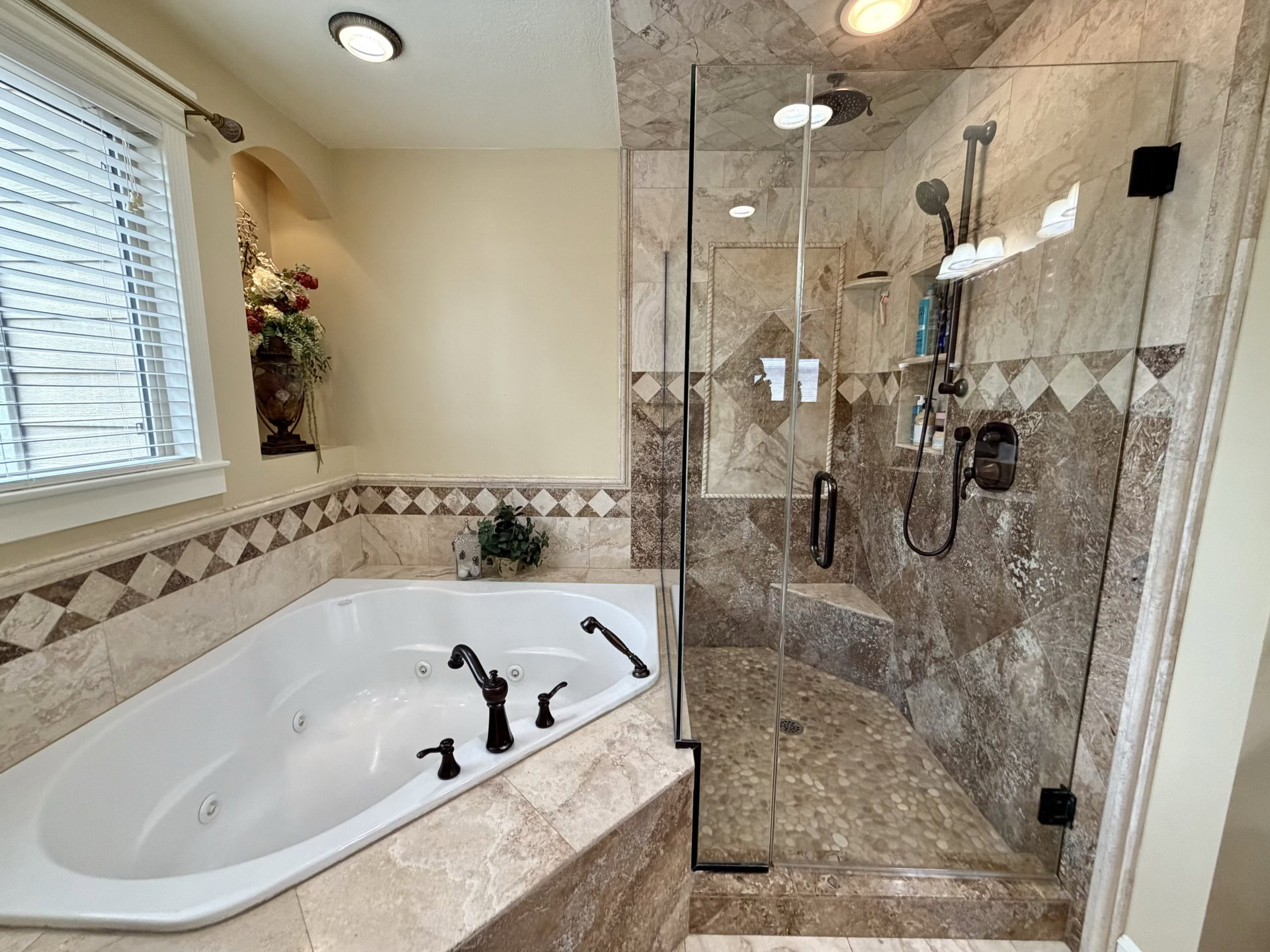 Tiled bathroom featuring a built-in jetted tub and a glass-enclosed shower