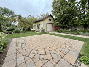 Circular paver patio with a contrasting border, surrounded by manicured lawn and mature landscaping