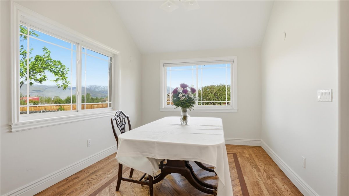 Bright room featuring two large windows with horizontal mullions, wood-finish flooring with a decorative inlay, clean white walls, and elegant baseboards