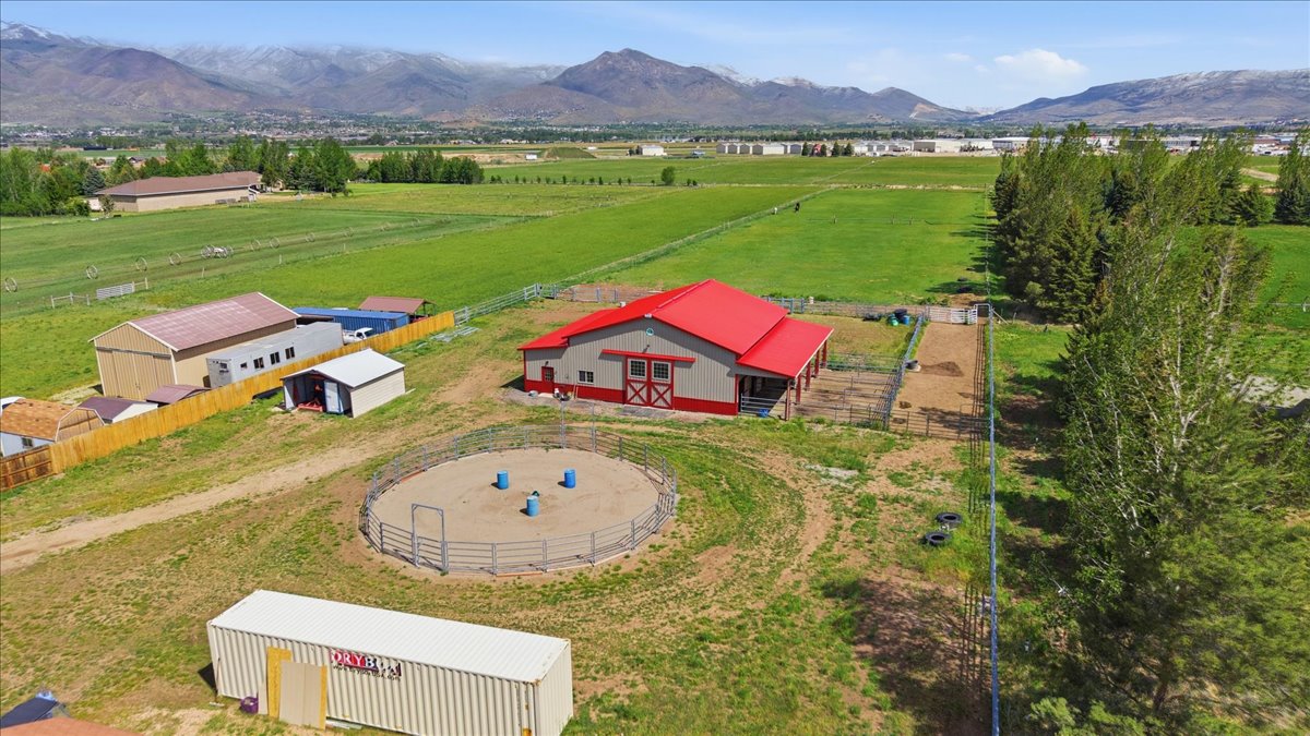 Expansive property featuring a red-roofed barn with red trim, a fenced round pen, and additional outbuildings