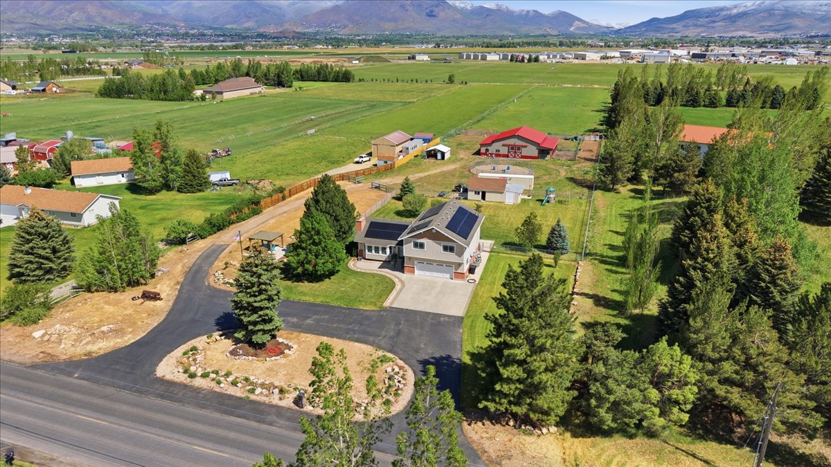 Two-story residence featuring an attached garage, solar panel installation, and a paved driveway with a central landscaped island