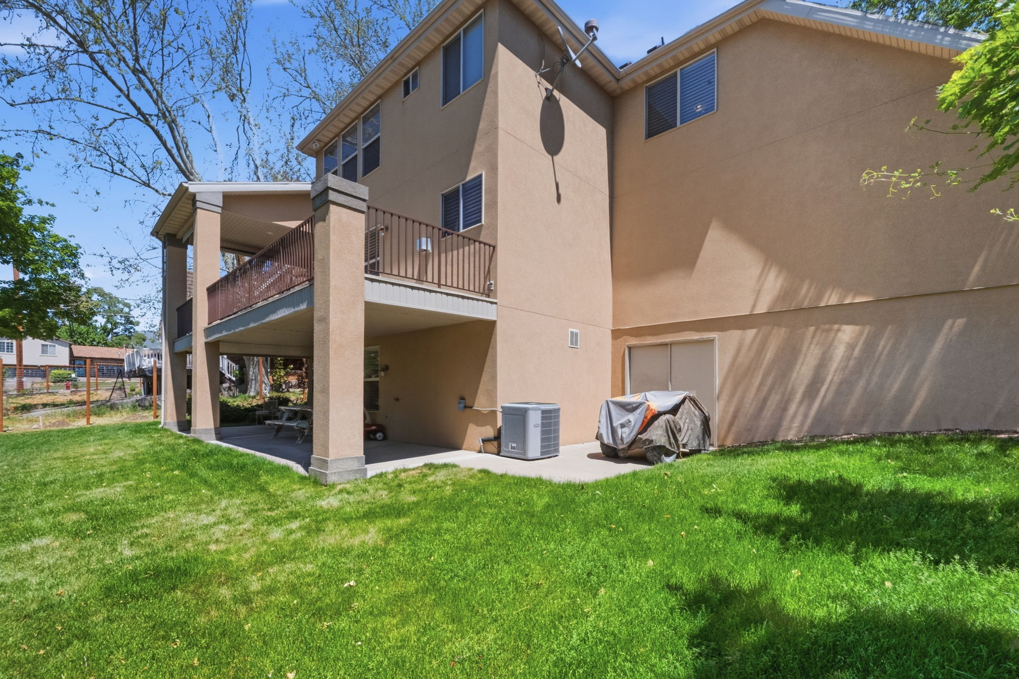 Exterior stucco siding featuring a two-story design with a ground-level patio and an upper-level covered balcony