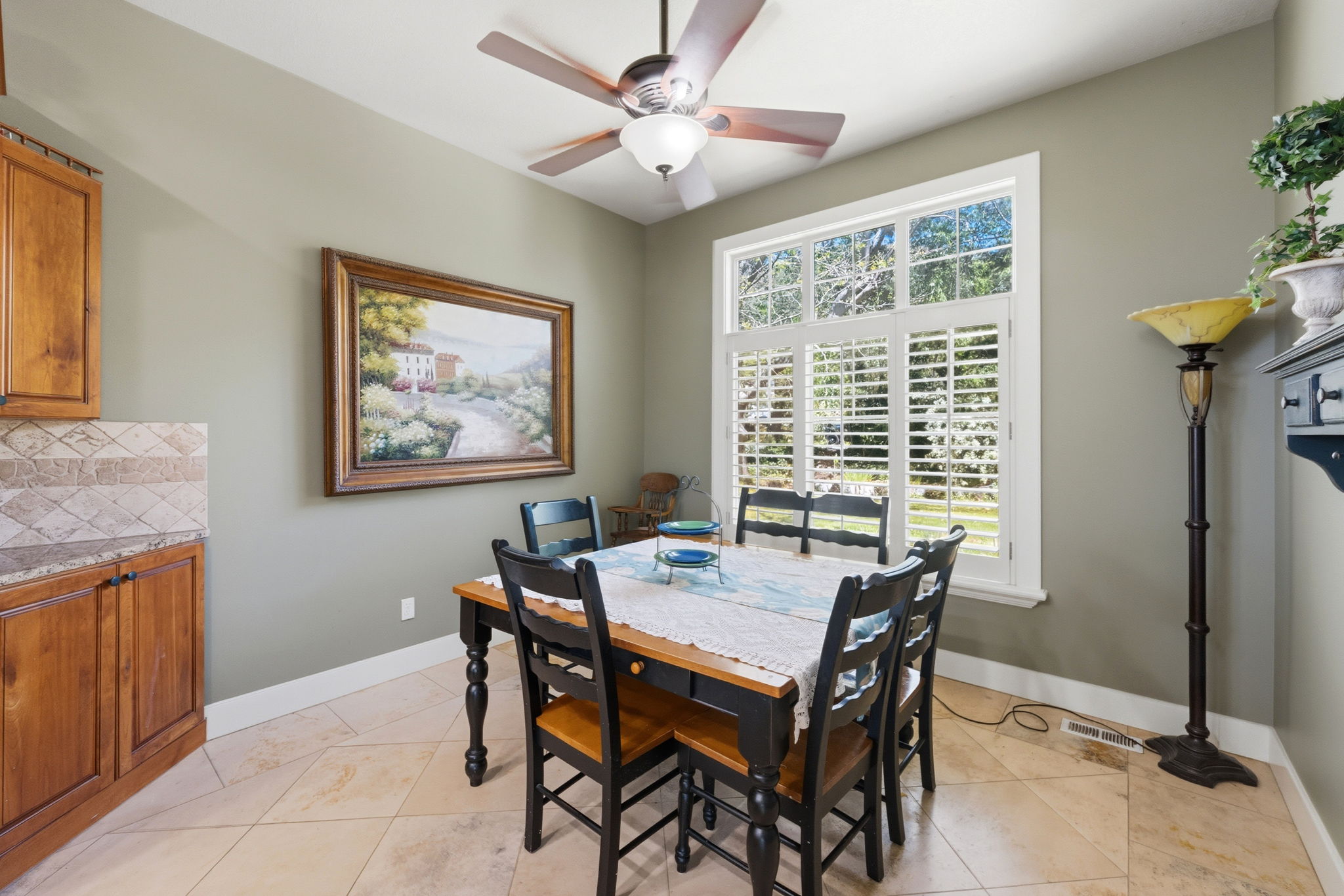 Dining area with a multi-paned window, plantation shutters, and a ceiling fan with integrated lighting