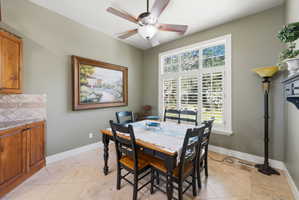 Dining area with a multi-paned window, plantation shutters, and a ceiling fan with integrated lighting