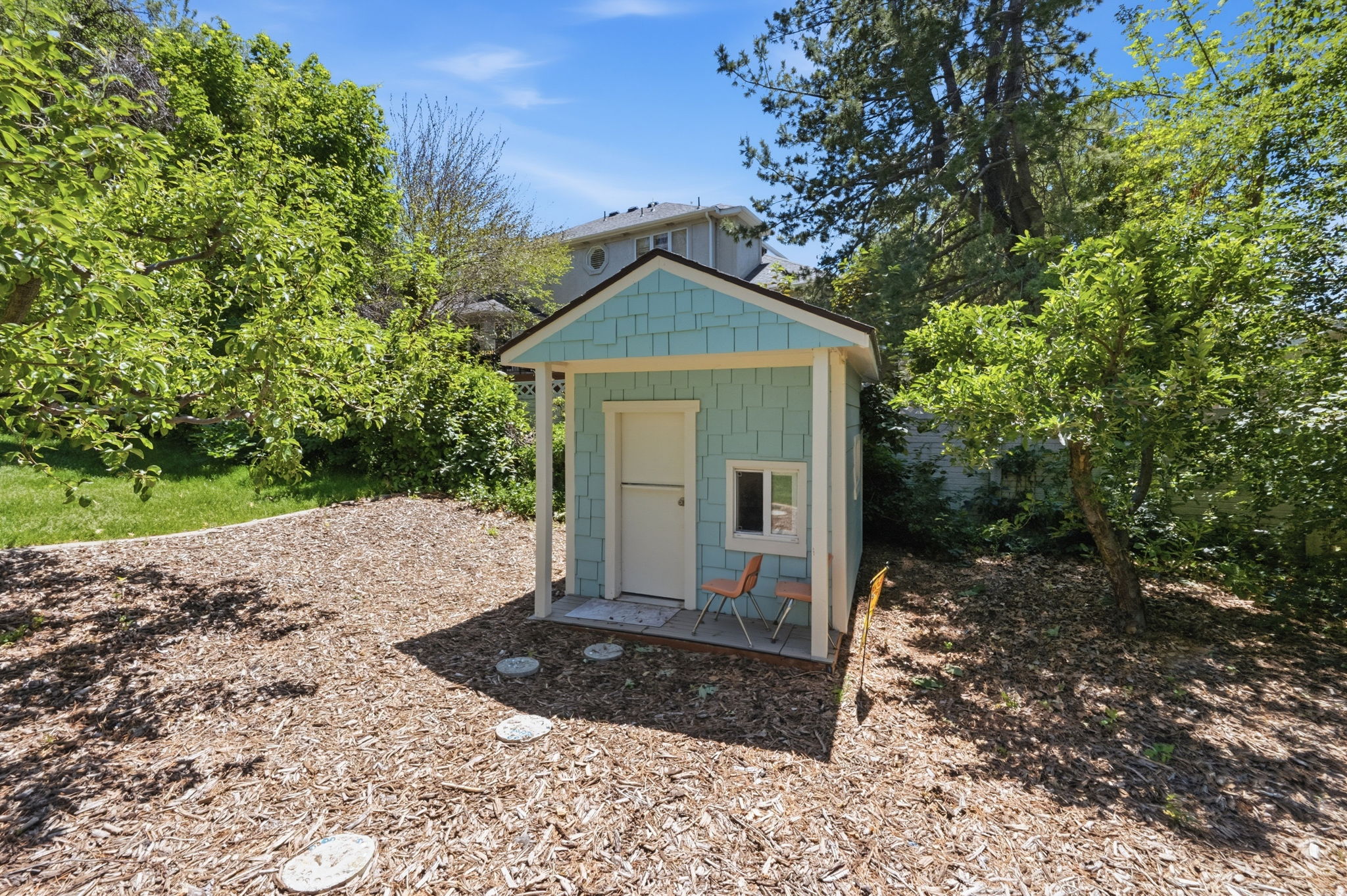 Light blue shingle-sided shed with a white trim and a small porch