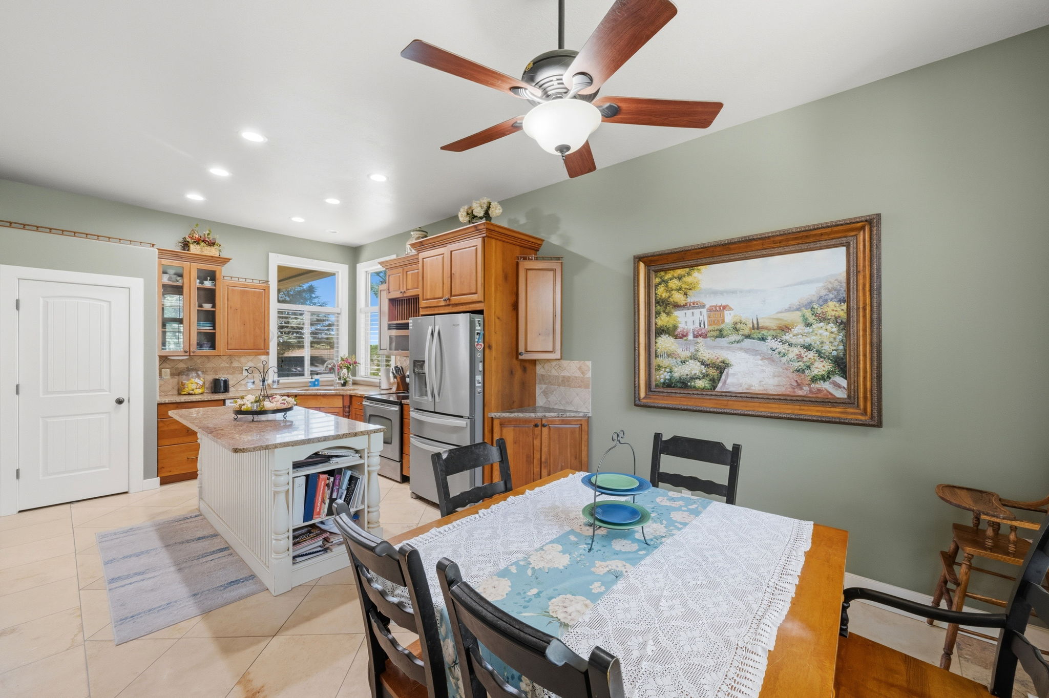 Open-concept kitchen and dining area featuring wood-finish cabinetry, a central island with a granite-style countertop, and stainless steel appliances
