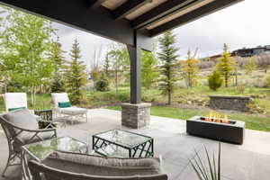 Covered patio featuring a concrete surface, stone-clad structural support, and a built-in fire pit
