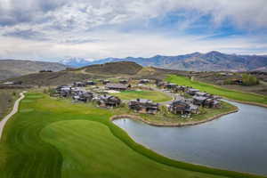 Expansive golf course community featuring modern residences, a tranquil lake, and mountain scenery