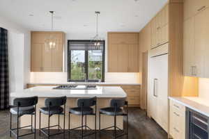 Modern kitchen featuring a large island with white countertops and an integrated cooktop