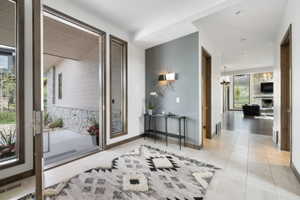 Spacious entry featuring a wide doorway with sidelights, neutral tile flooring, and wood-trim accents