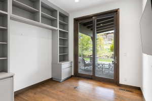 Built-in shelving and cabinetry with gray finish, wood-finish flooring, sliding glass door, and recessed lighting