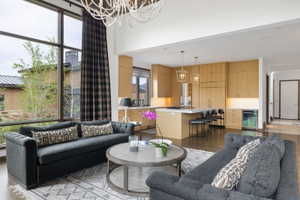 Open-concept living space featuring high ceilings, expansive window wall with dark framing, and wood-finish flooring