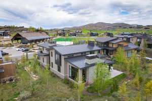 Contemporary residence featuring multiple stone and stucco facades, a metal seam roof, and chimney accents