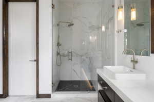 Modern bathroom featuring a frameless glass shower enclosure with white marble-patterned tile walls and a dark tile shower pan