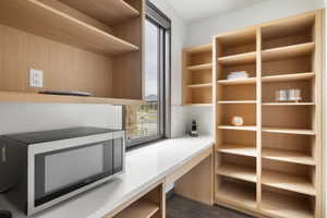 Built-in wood-finish shelving and cabinetry featuring a white countertop and a large window