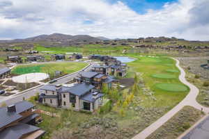 Modern residential community featuring contemporary homes with metal roofs, a golf course with multiple greens, and a paved pathway