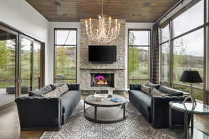 Living area featuring a stone fireplace, wood-finish ceiling, large picture windows, and glass doors to an exterior patio