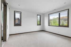 Spacious room featuring light-colored carpeting, white walls, and recessed lighting