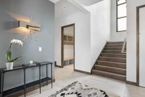 Foyer featuring wood-finish staircase, tile flooring, and contrasting wall colors