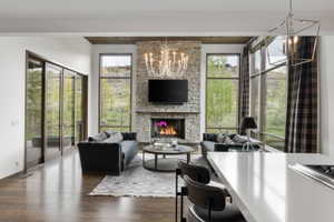 Living area featuring a floor-to-ceiling stone fireplace, wood-finish flooring, and expansive windows