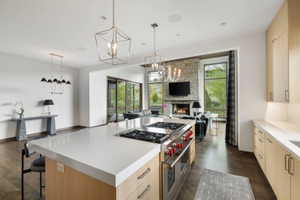 Open-concept kitchen featuring a built-in range, a large central island with light-toned countertop, and light wood-finish cabinetry