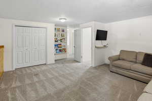 Carpeted room featuring a built-in shelving unit, a wall-mounted floating shelf, and a closet with bifold doors