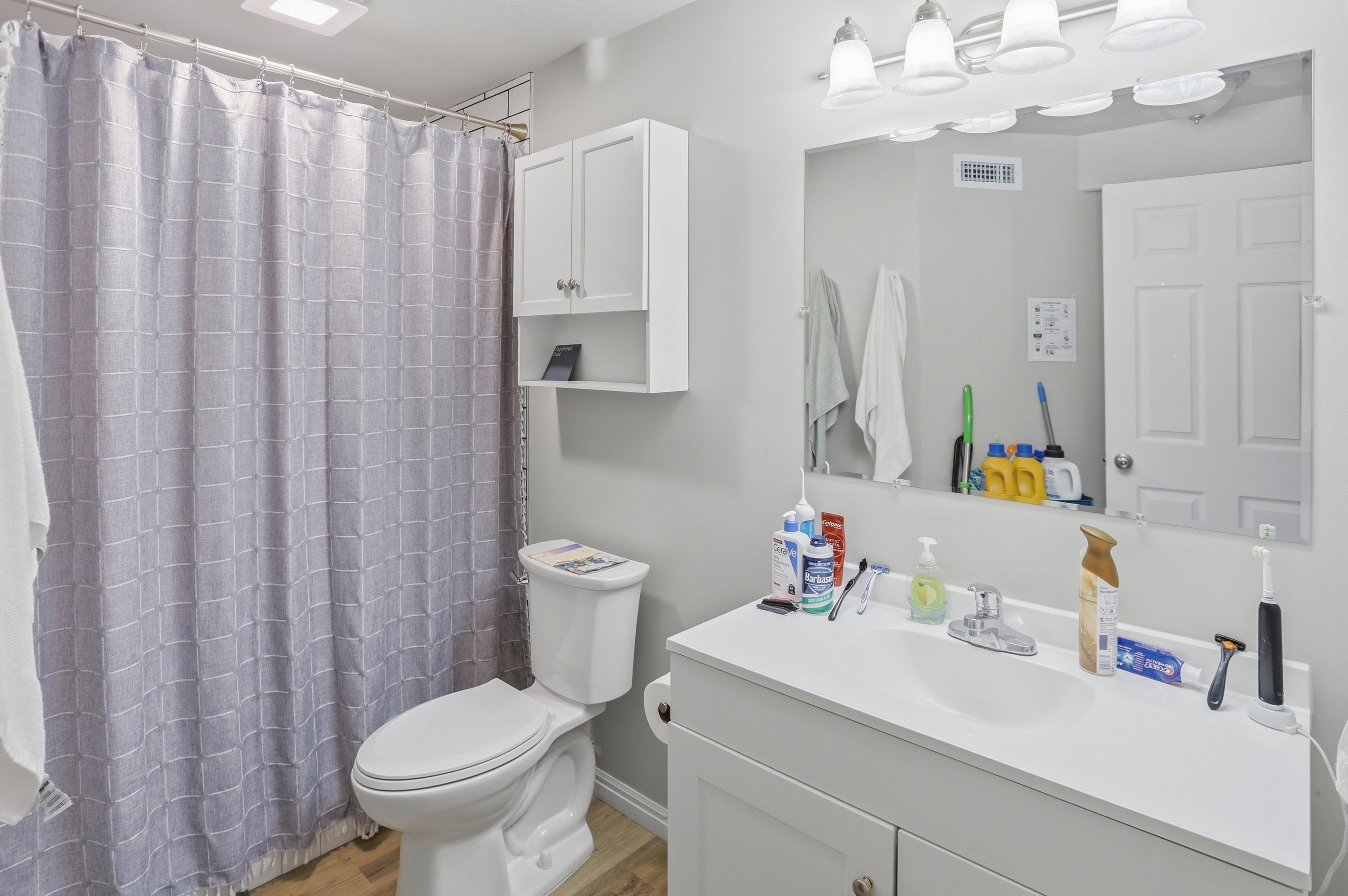 Basement apartment bathroom featuring a single vanity with an integrated sink, large wall-mounted mirror, and overhead vanity lighting