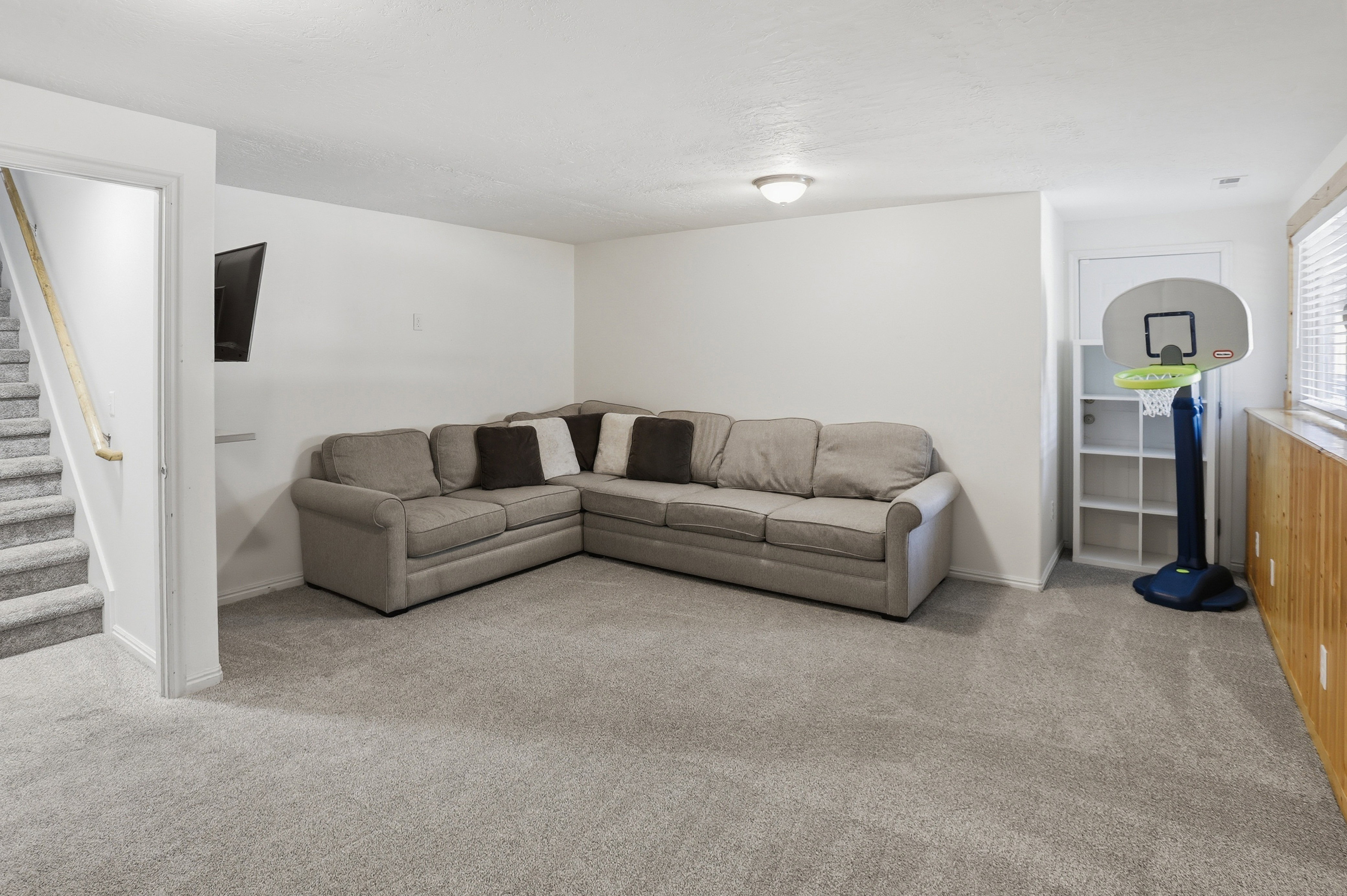 Spacious lower-level area featuring light gray carpet, white walls, and a recessed ceiling light