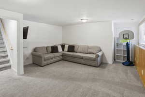 Spacious lower-level area featuring light gray carpet, white walls, and a recessed ceiling light