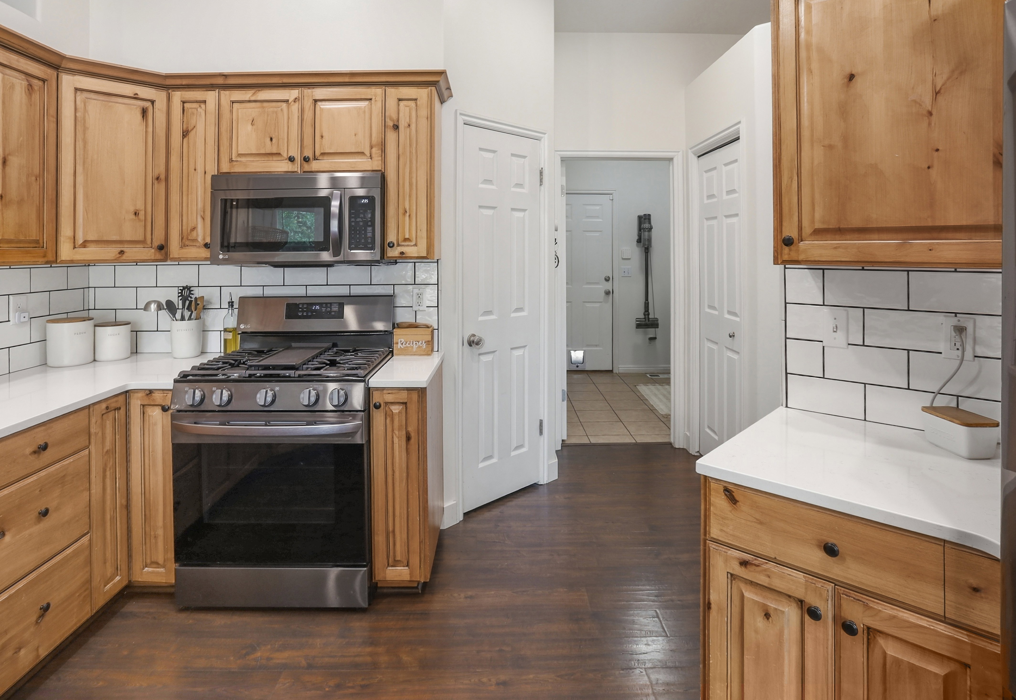 Kitchen featuring wood cabinetry, white countertops, subway tile backsplash, stainless steel gas range, and matching microwave