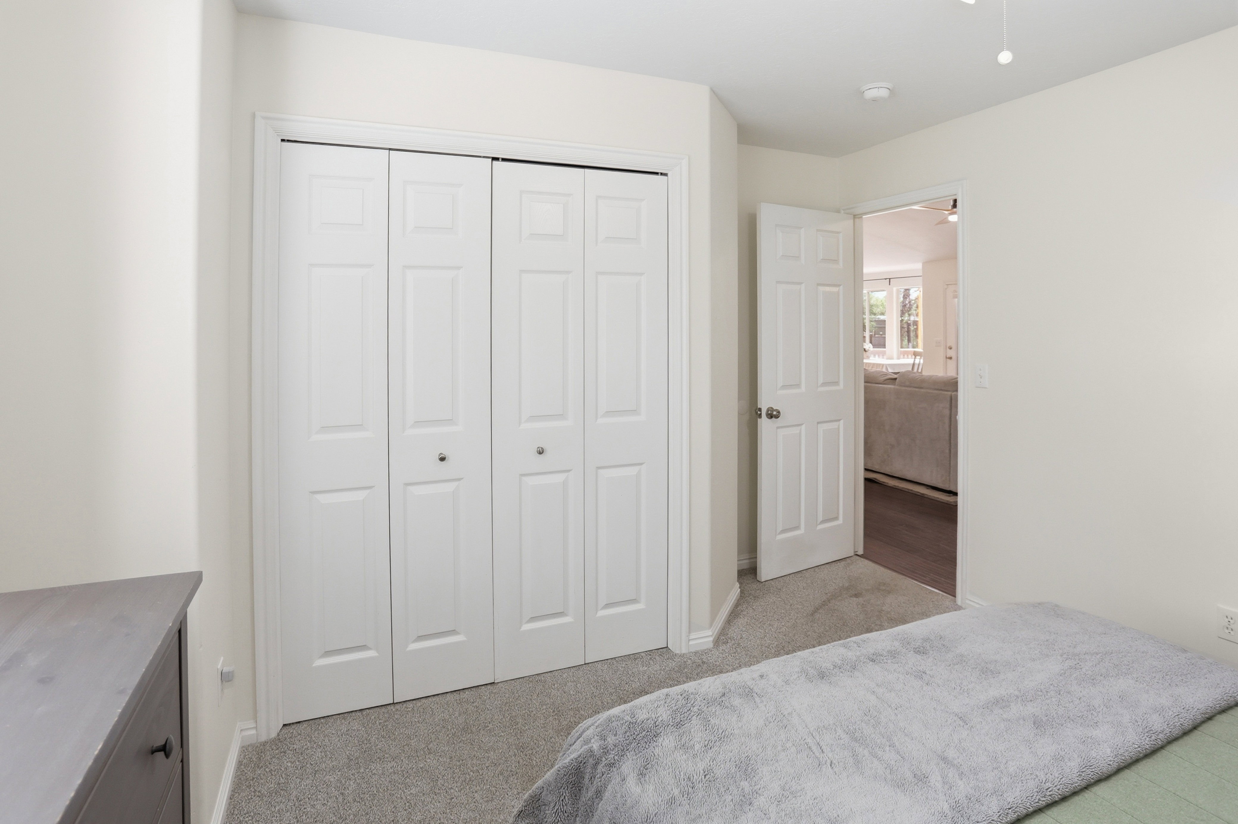 Bedroom featuring neutral-toned walls, gray carpet flooring, and a bi-fold closet with white panel doors